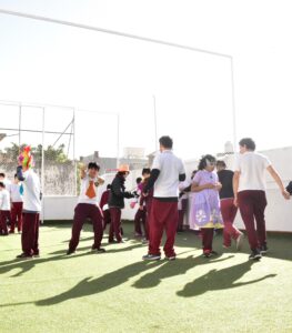 alumnos disfrazados corriendo y bailando en el patio